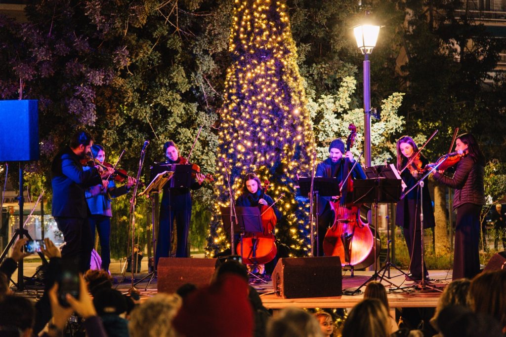 Ορχήστρα κλασικής μουσικής παίζει μπροστά από Χριστουγεννιάτικο δέντρο